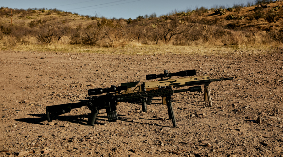 A couple of guns sitting on top of a dirt field